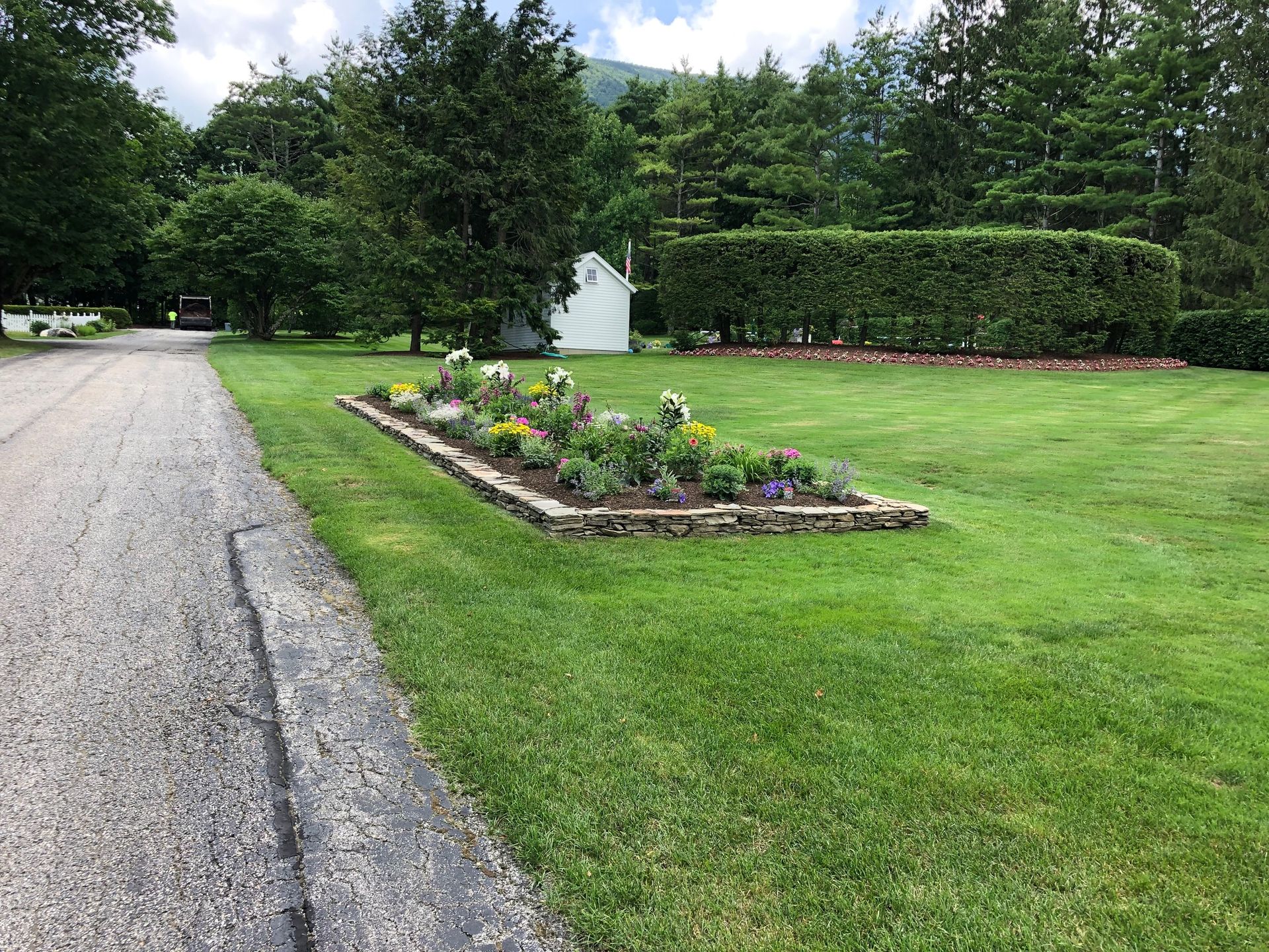 A gravel road with a flower bed in the middle of it.