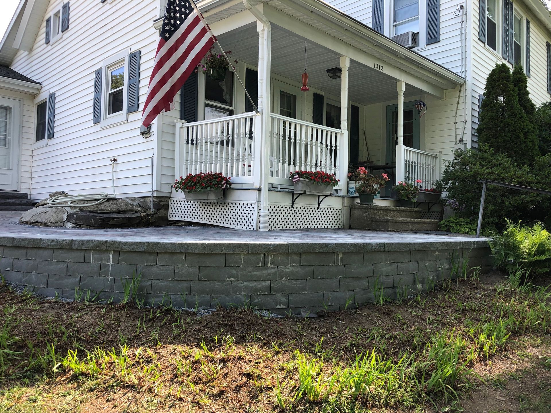 A white house with a porch and an american flag on it.