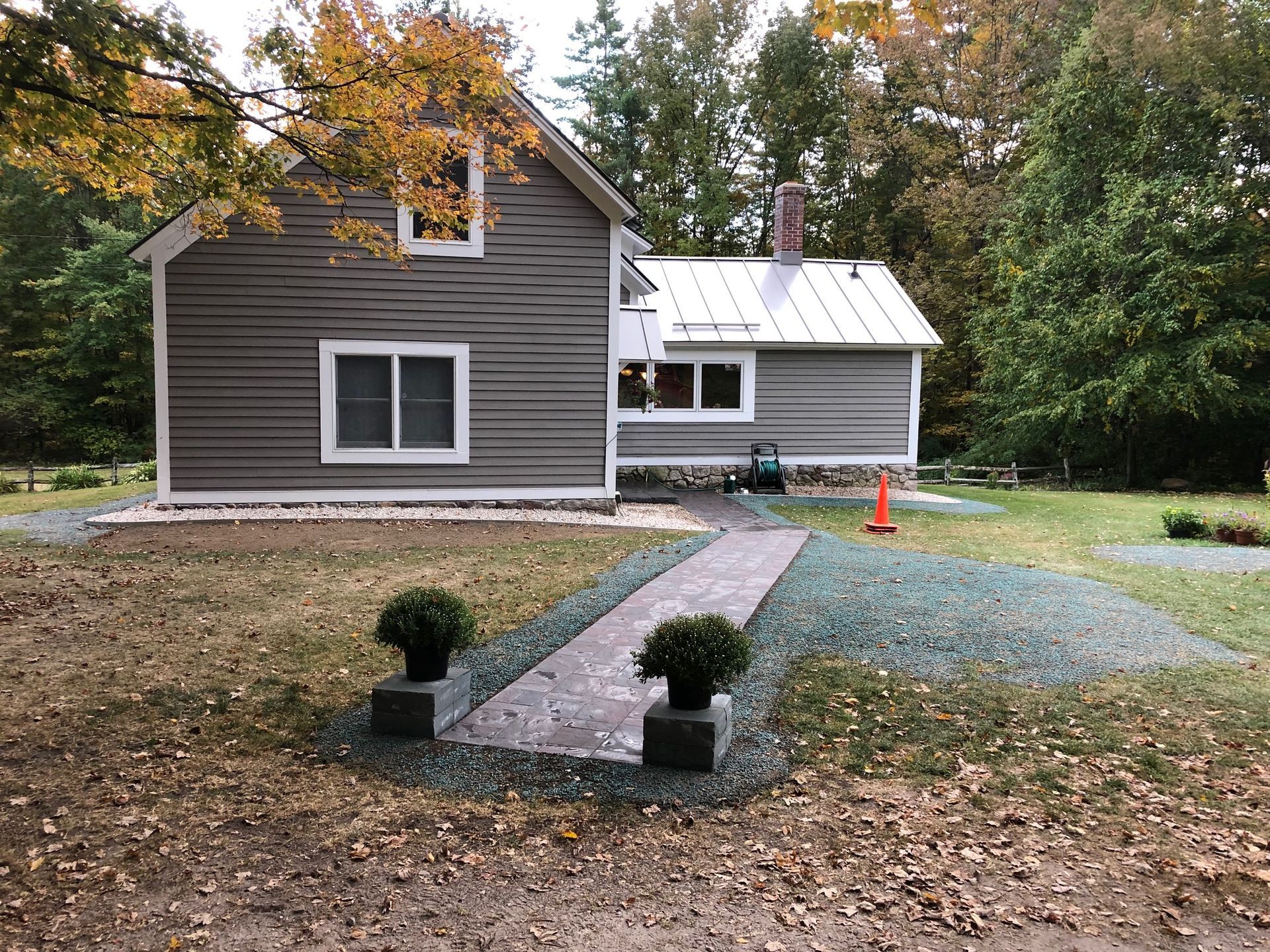 A small house with a metal roof and a walkway leading to it.