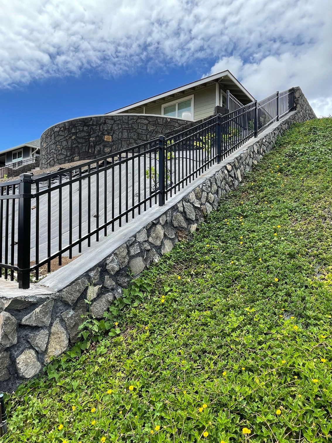 There is a fence surrounding a house on a hill.