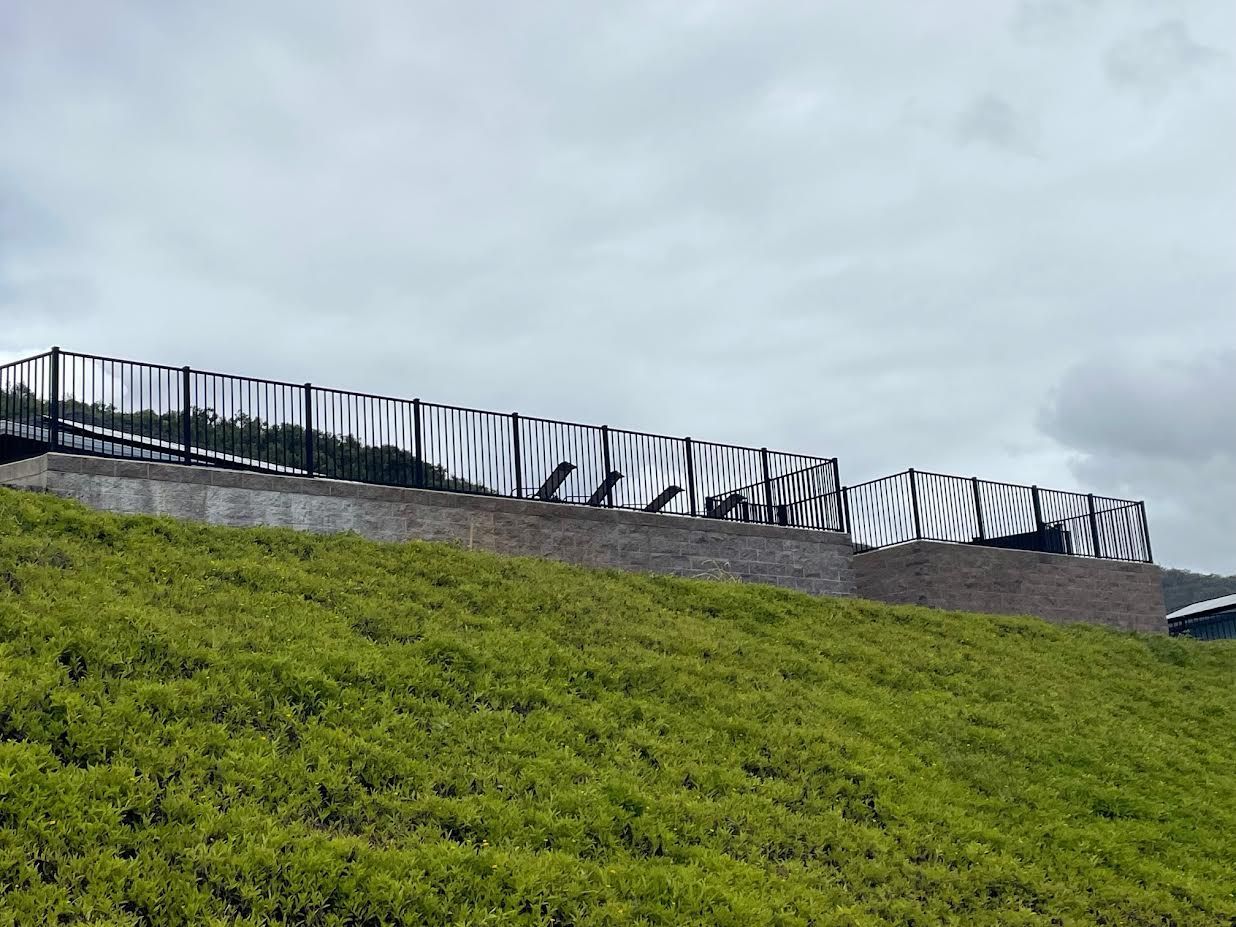 A fence is sitting on top of a lush green hillside.