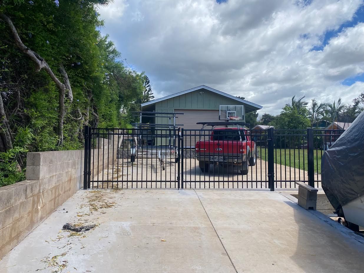 A red truck is parked in front of a house behind a gate.