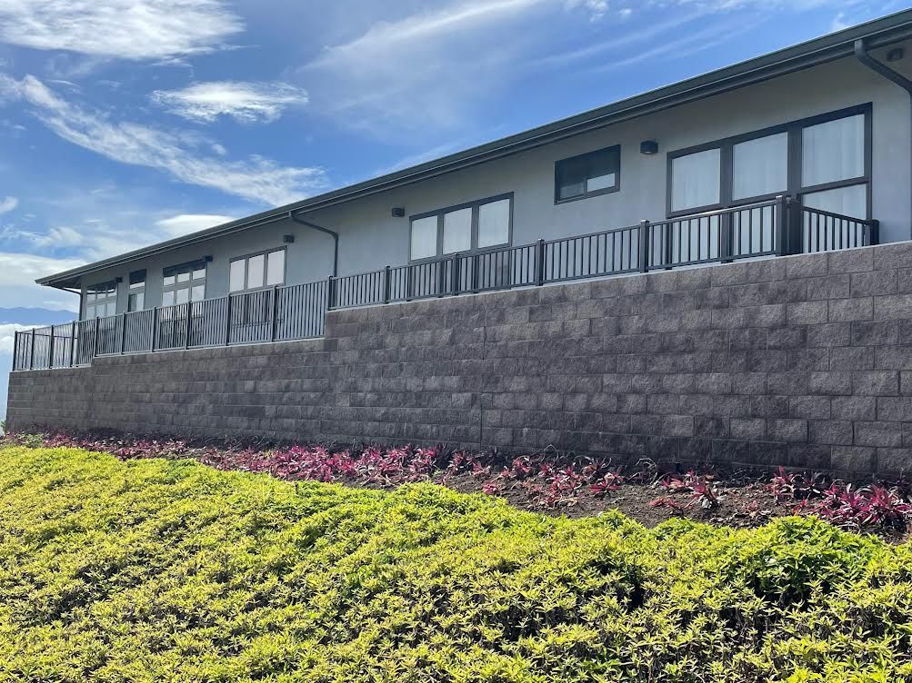 A large white building with a brick wall and a balcony.