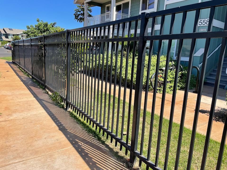 A black metal fence surrounds a sidewalk in front of a building.