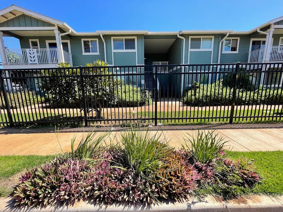 A house with a fence around it and flowers in front of it