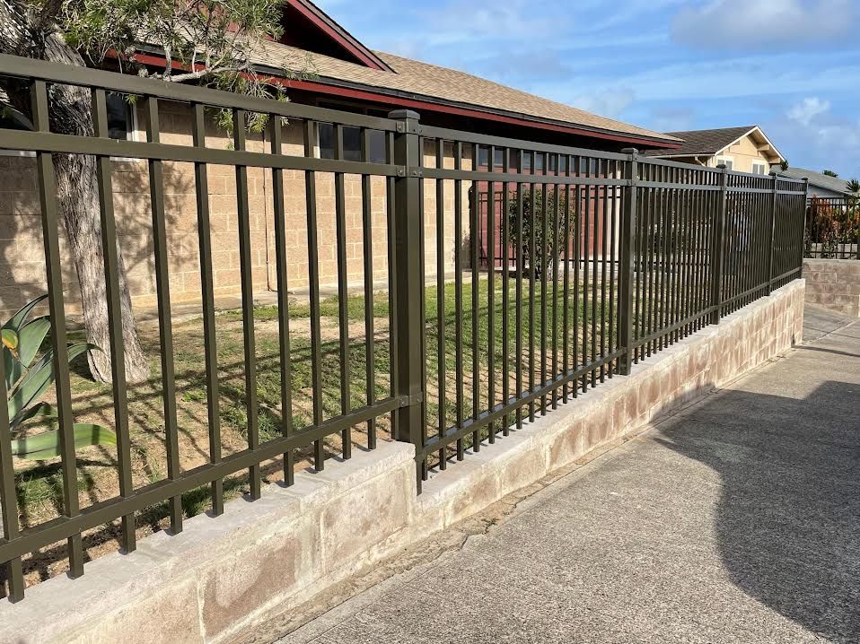 A metal fence surrounds a brick wall in front of a house.