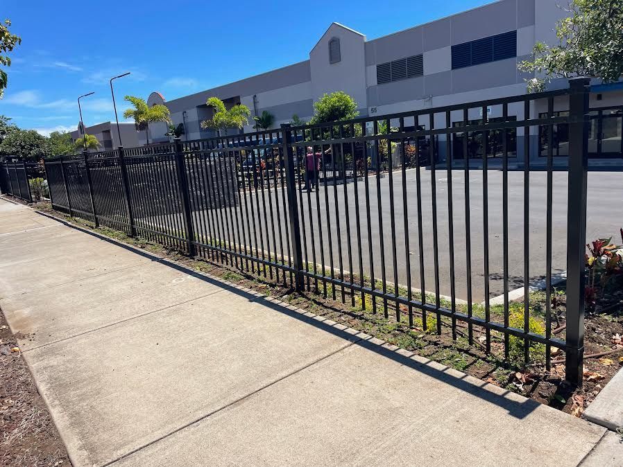 A metal fence along a sidewalk in front of a building.