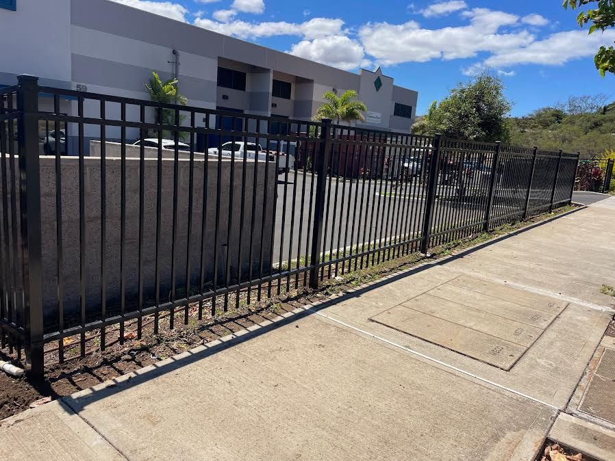 A black metal fence along a sidewalk in front of a building.