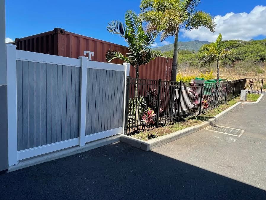 A white and gray fence with a red shipping container in the background.