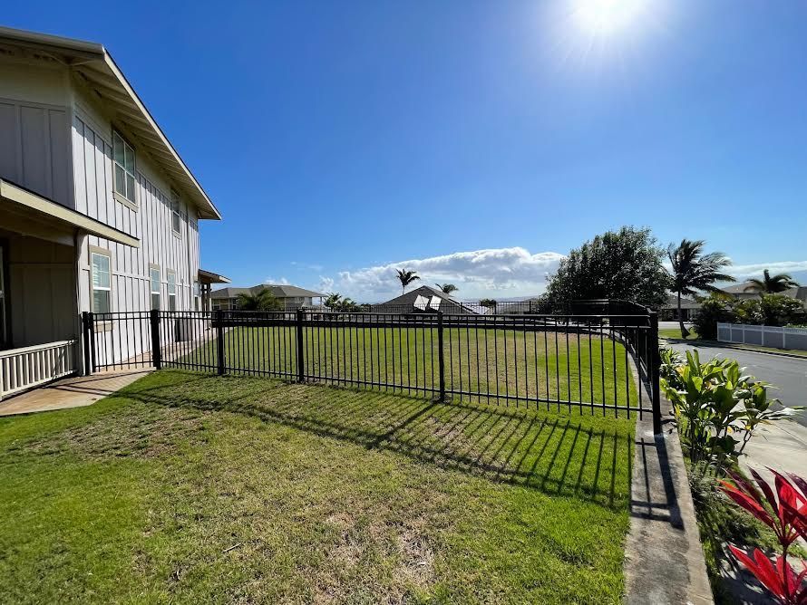 A fence surrounds a lush green field in front of a house.