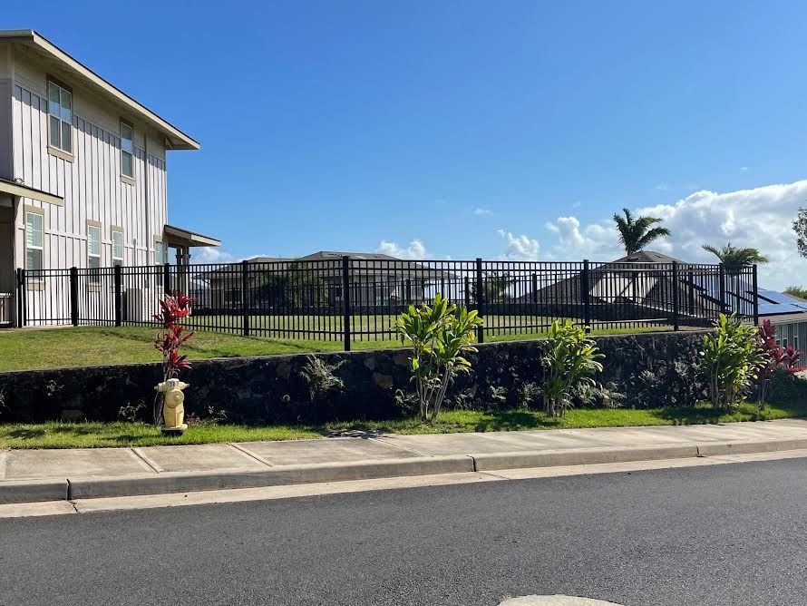 A fire hydrant is in front of a house with a fence around it.