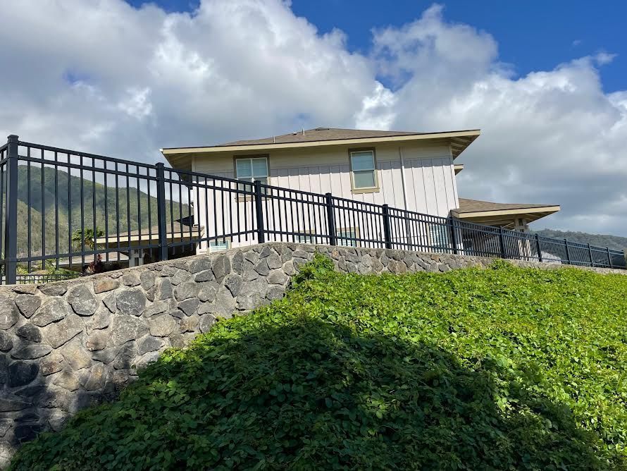 A house with a fence around it is sitting on top of a hill.