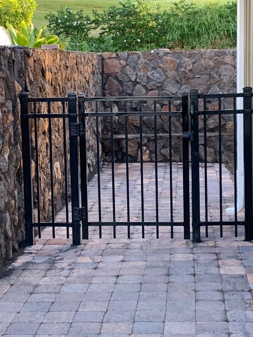 A black gate with a stone wall in the background