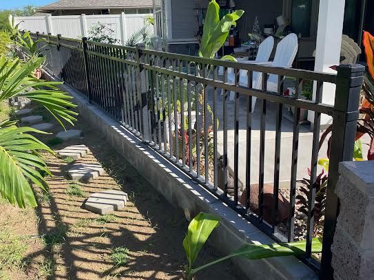 A black metal fence surrounds a patio with chairs.
