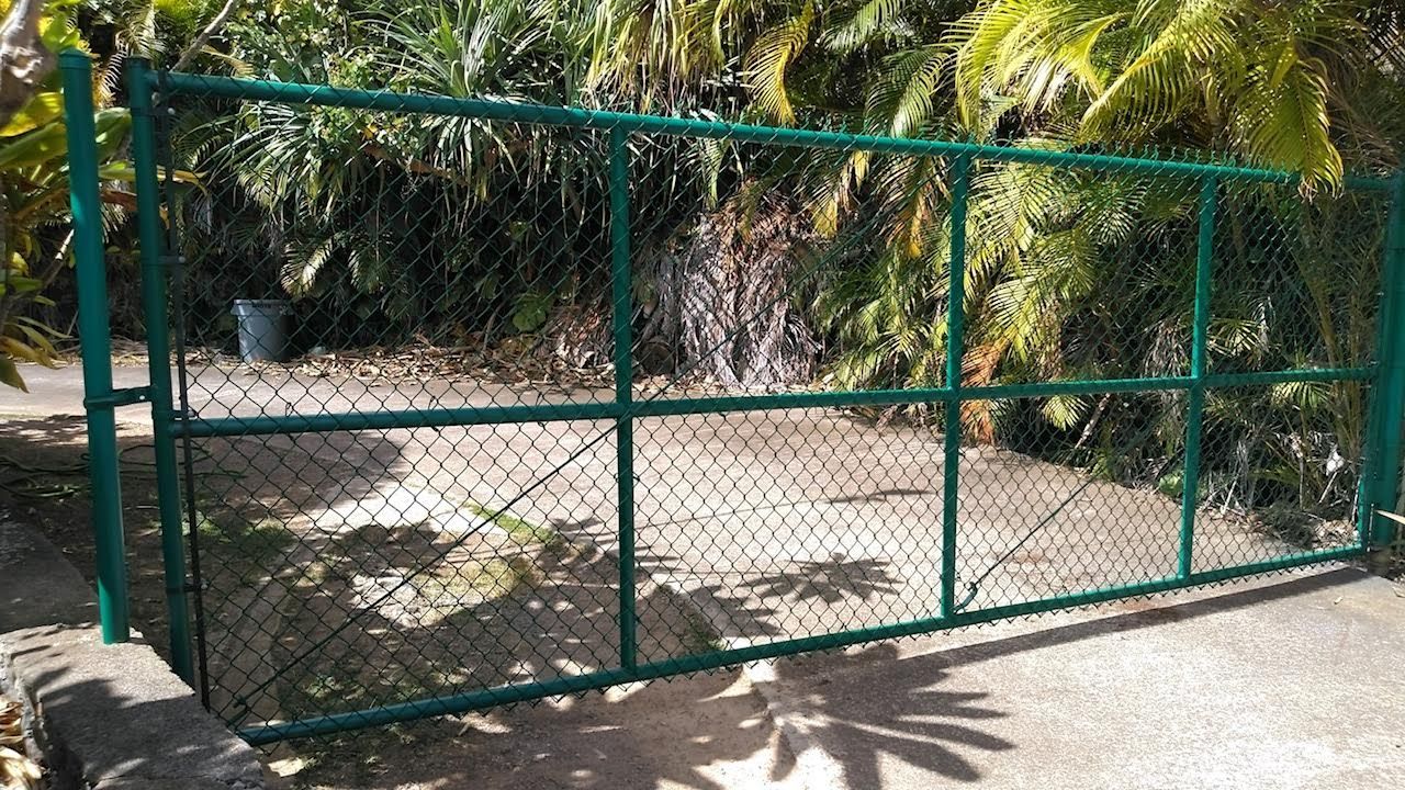 A green chain link fence is sitting on top of a concrete driveway.