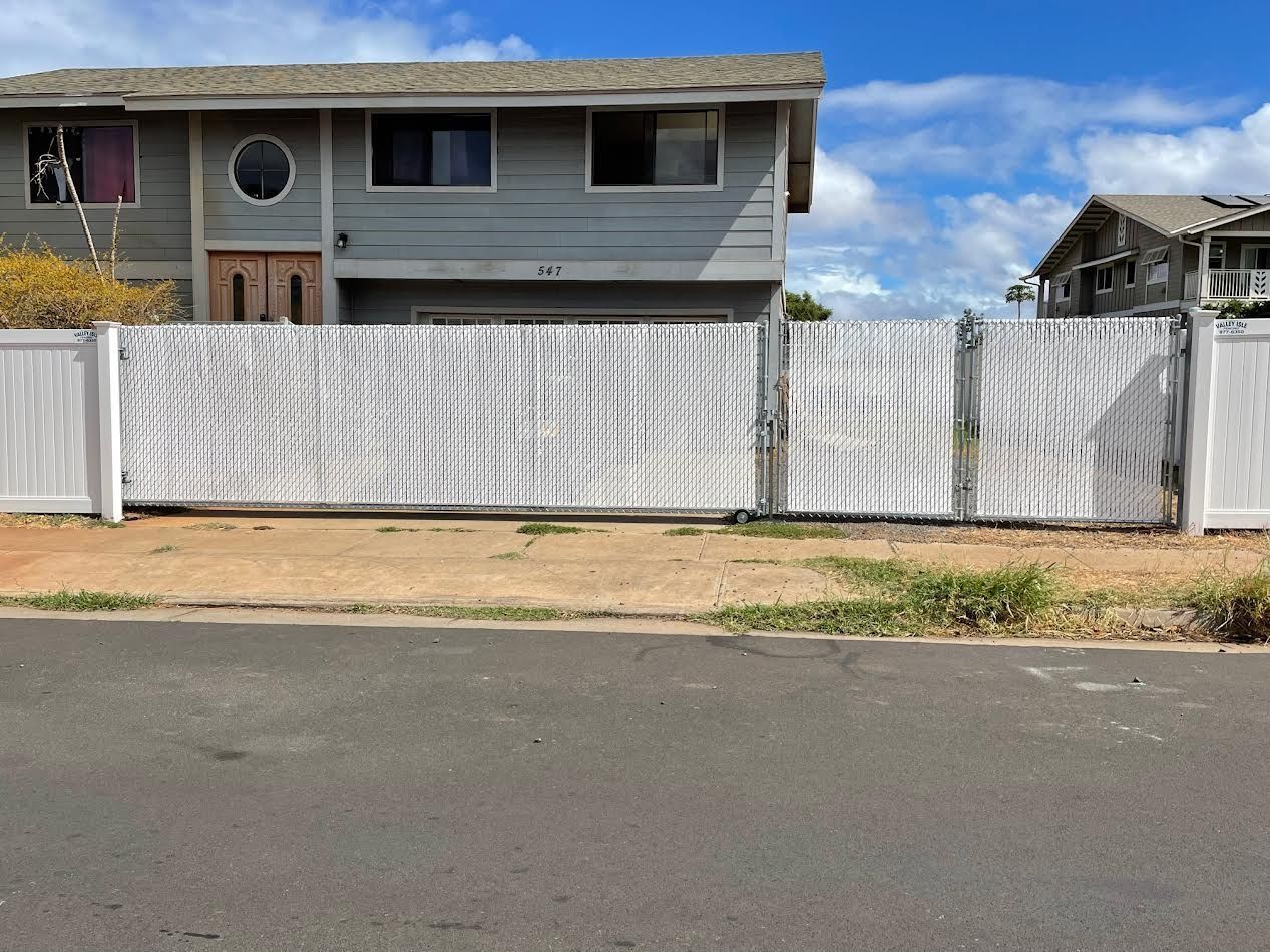 A house with a white fence and a sliding gate in front of it