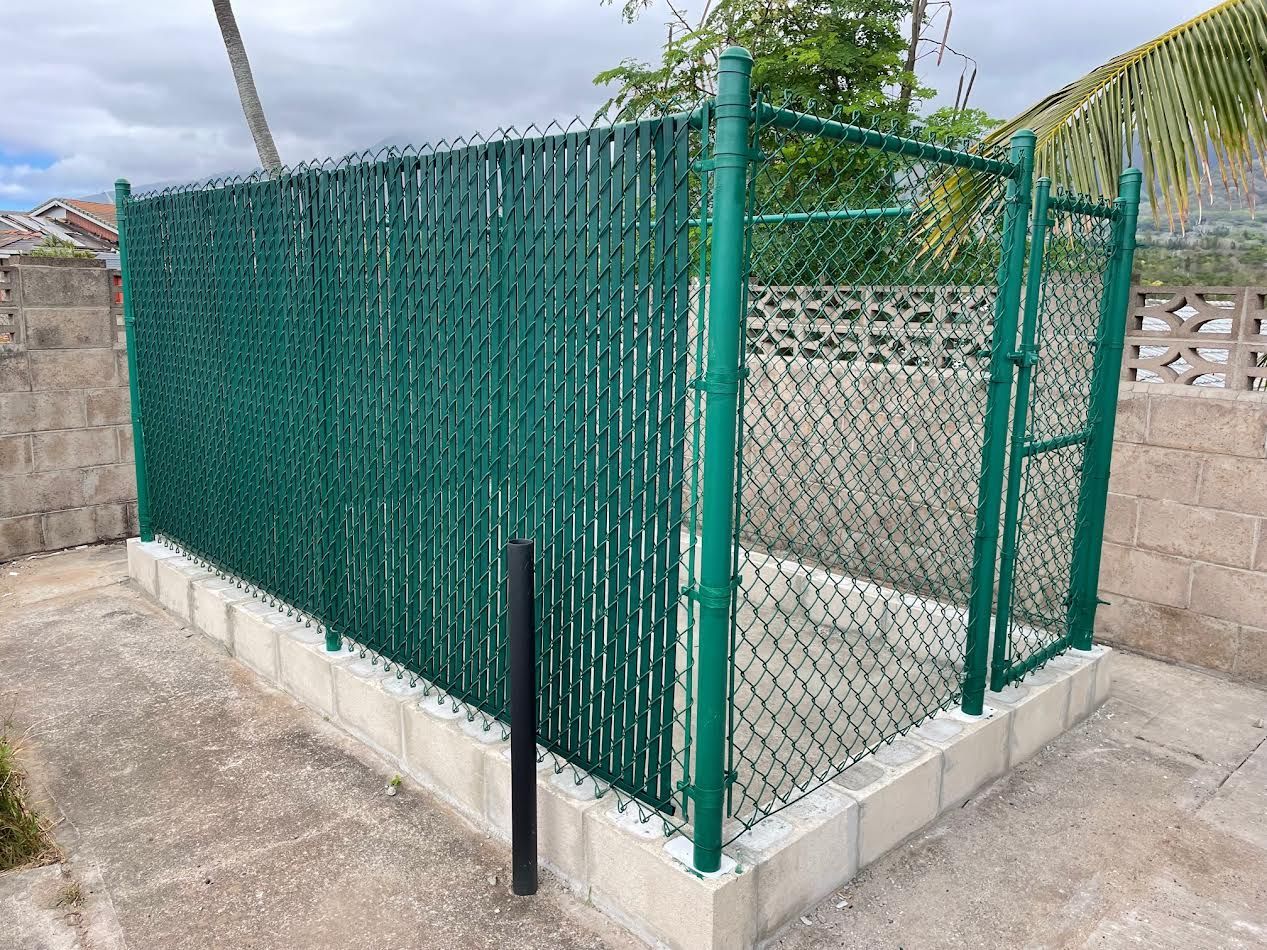 A green chain link fence with a gate is surrounding a building.