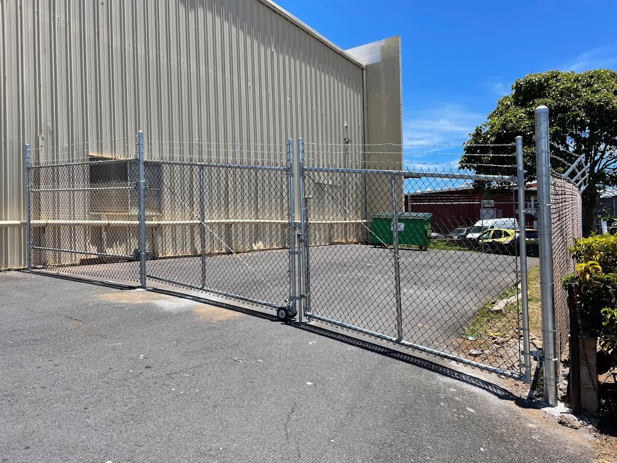 A chain link fence is surrounding a parking lot in front of a building.