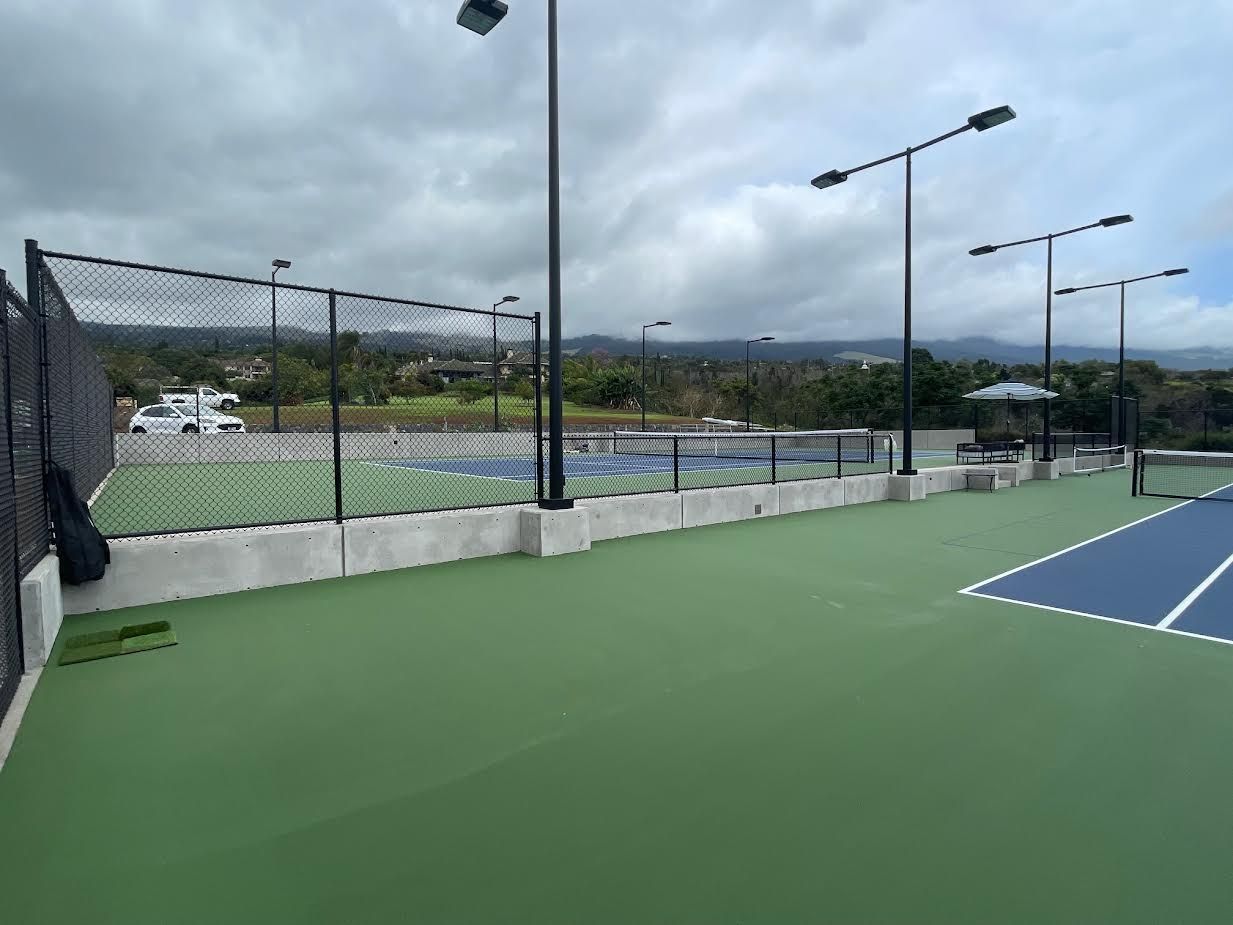A tennis court with a fence around it on a cloudy day.