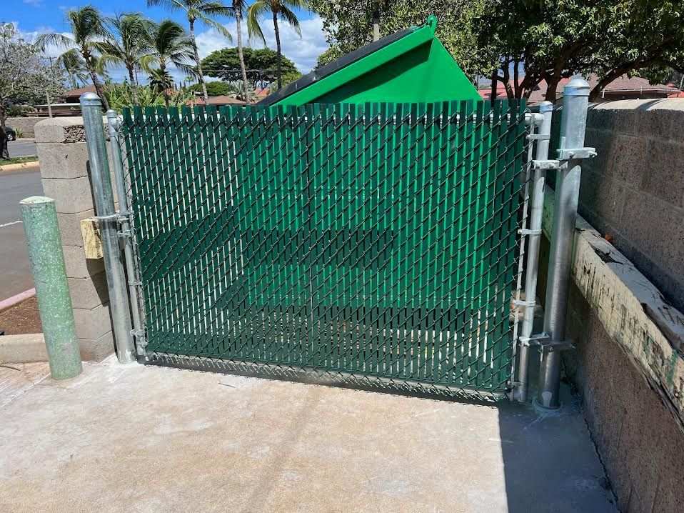 A green chain link fence with a green trash can in the background.