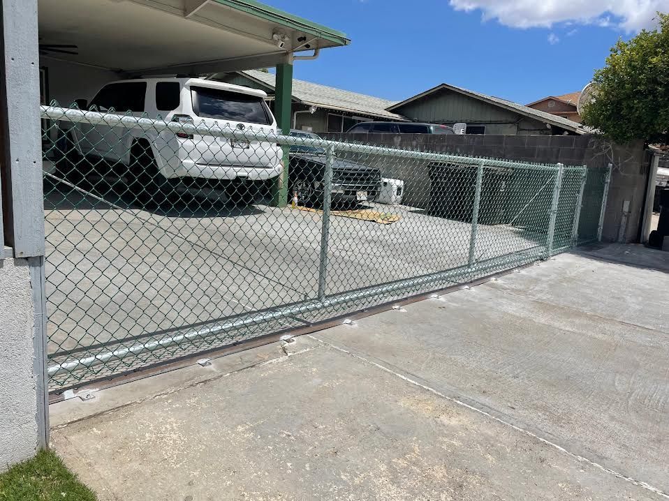 A white suv is parked in a driveway behind a chain link fence.