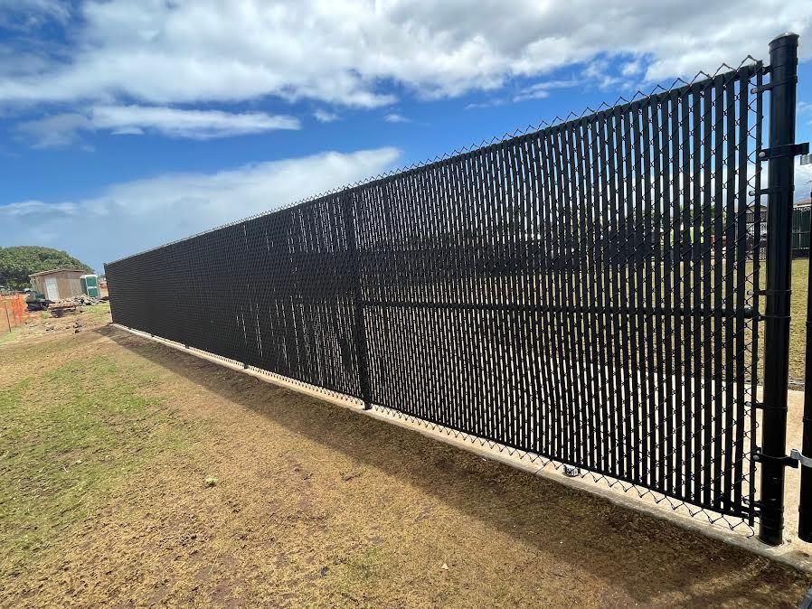 A black chain link fence is sitting on top of a dirt field.