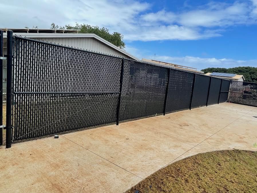 A black chain link fence is sitting on a sidewalk in front of a house.