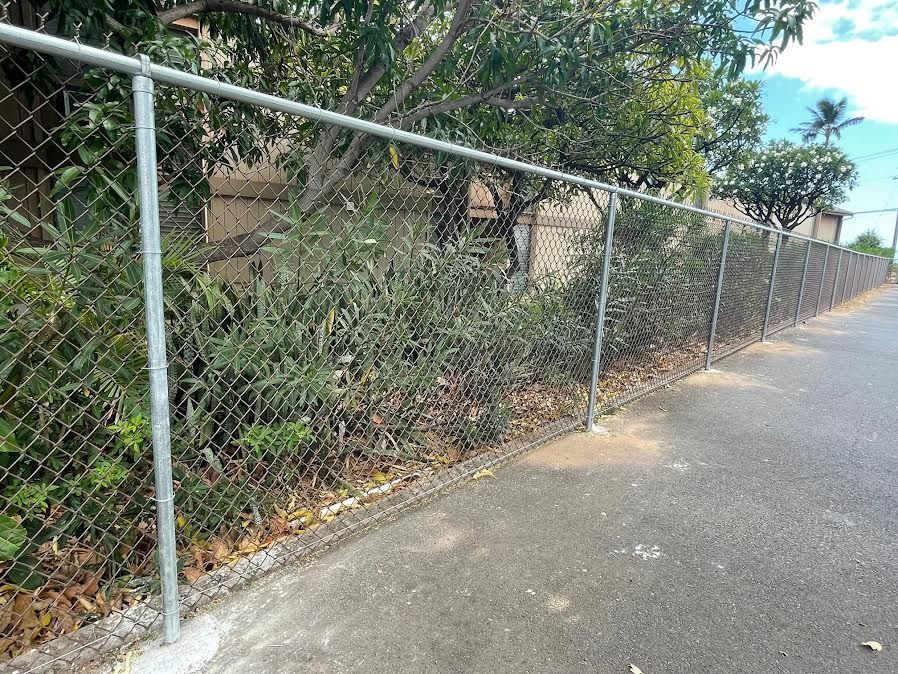 A chain link fence is along the side of a road.