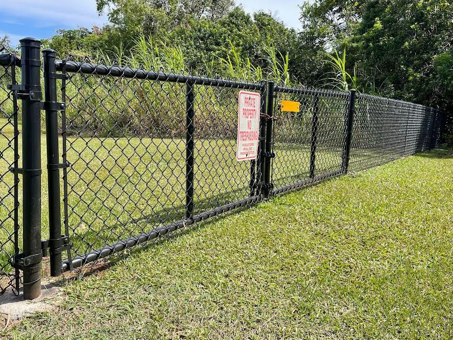A black chain link fence is surrounding a grassy field.