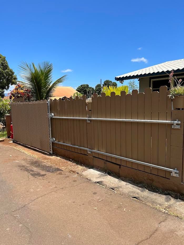 A wooden fence is along the side of a road next to a house