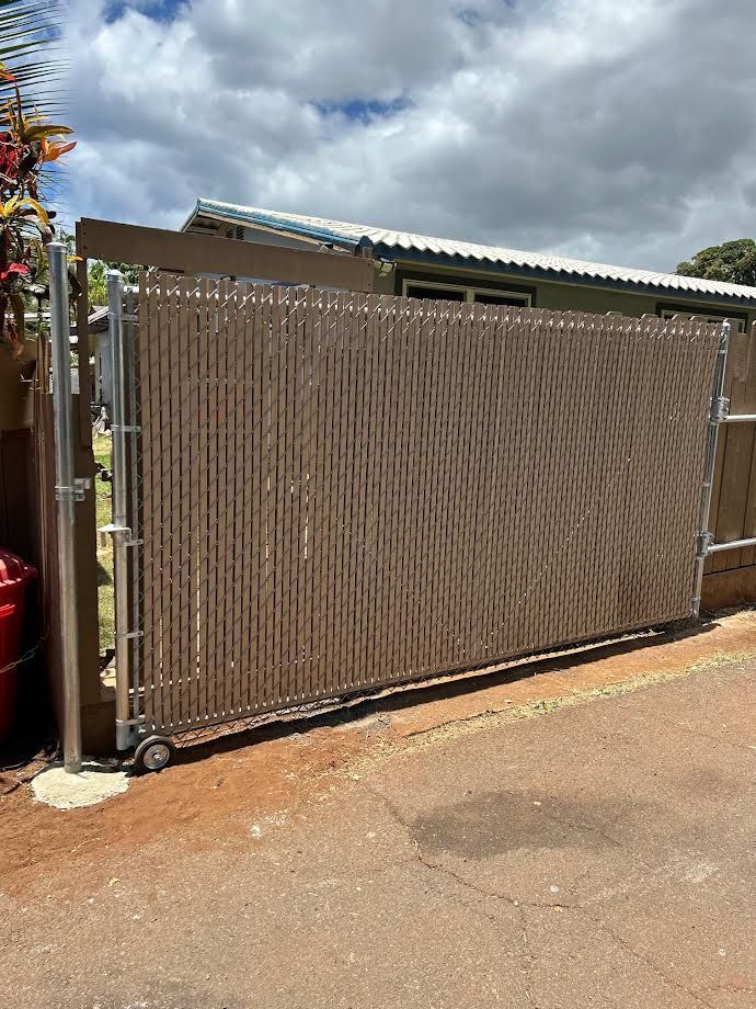 A sliding gate is sitting on the side of the road in front of a house.