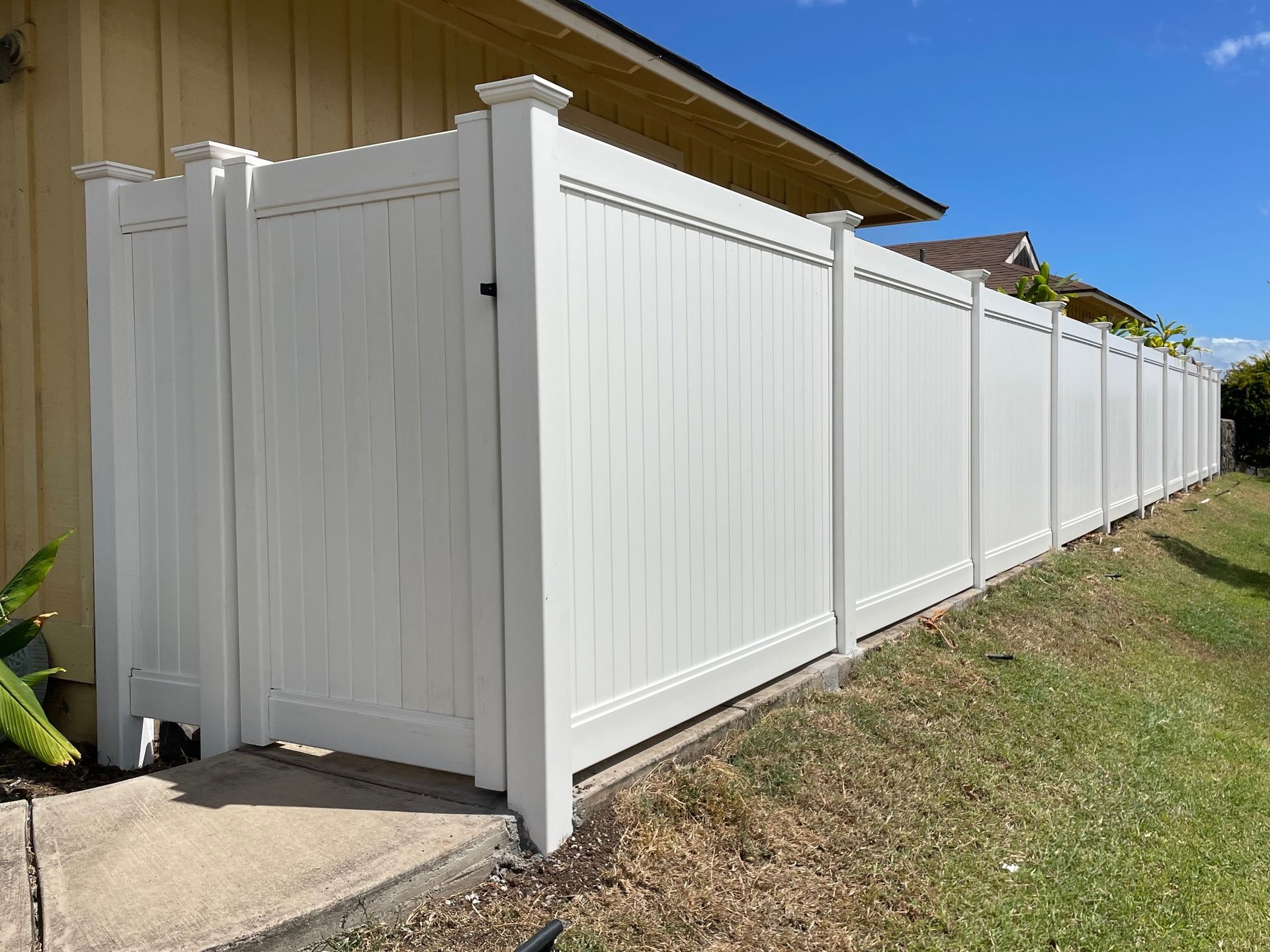A white fence with a gate in front of a house.