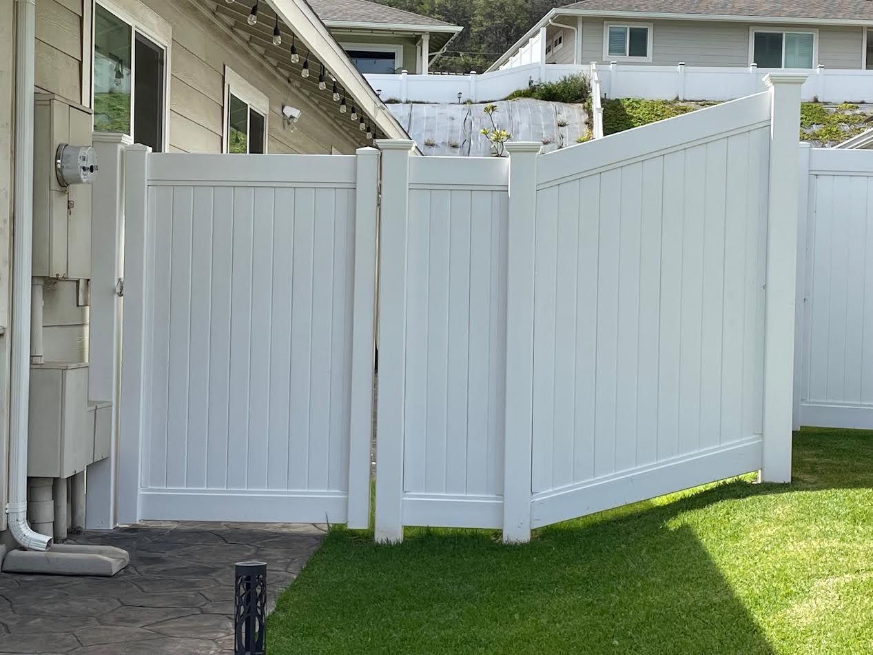 A white fence is in the backyard of a house.