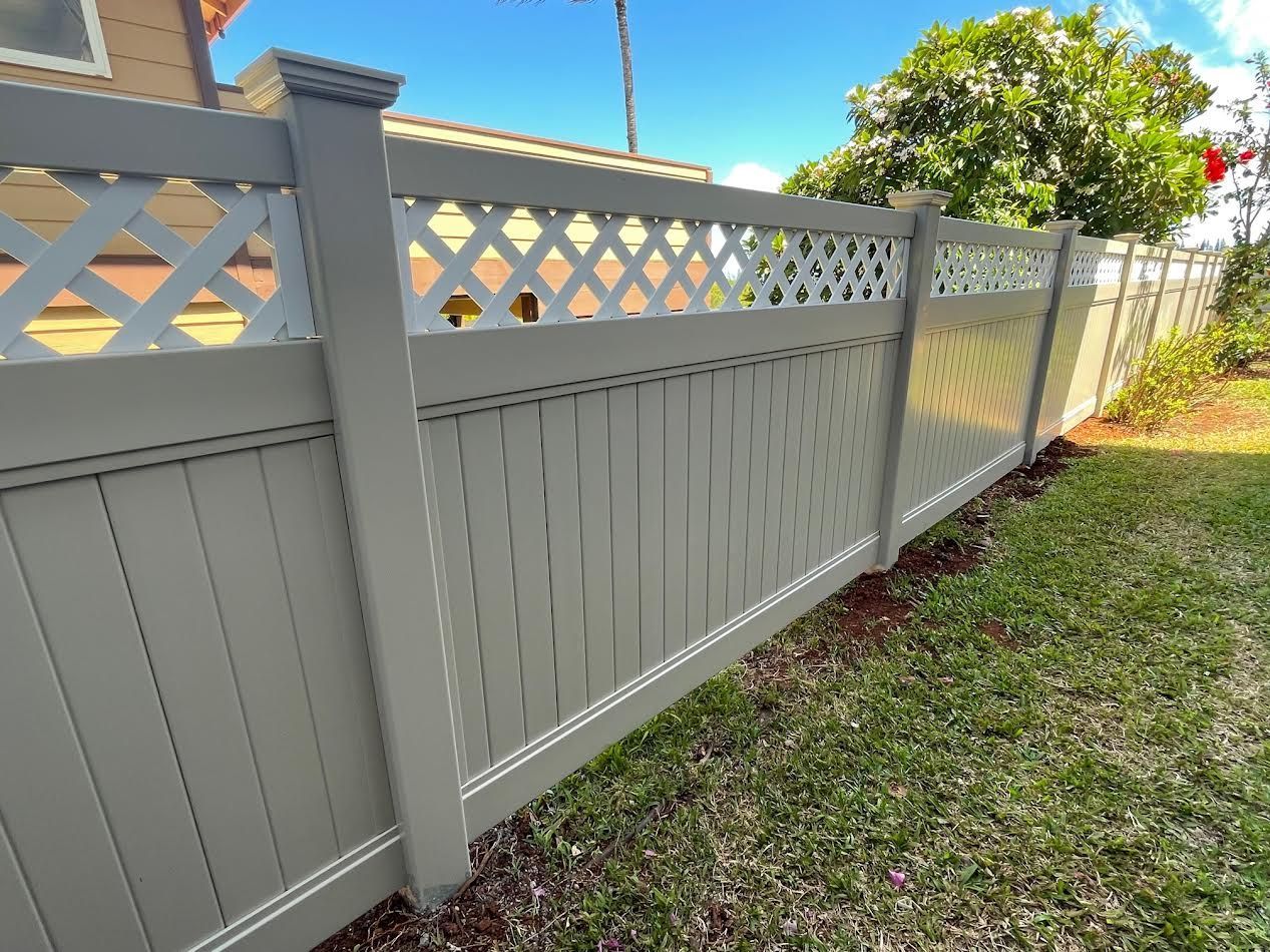 A gray wooden fence with a lattice design is in the backyard of a house.
