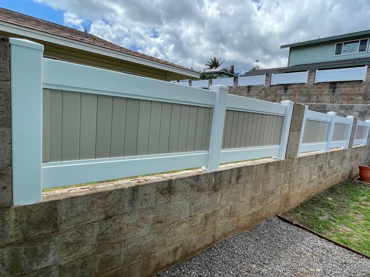 A white fence is sitting on top of a brick wall.