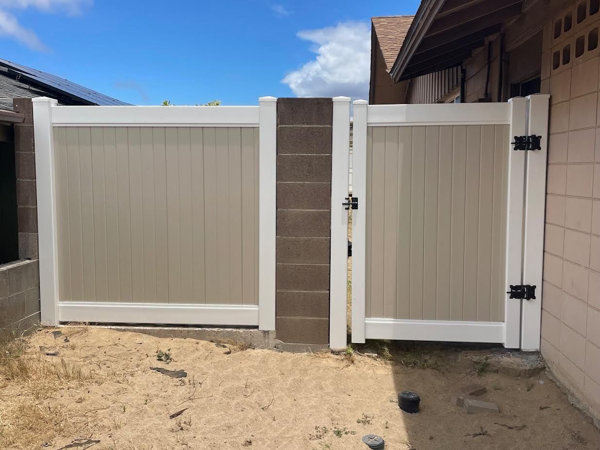 A white fence with a gate in the backyard of a house.
