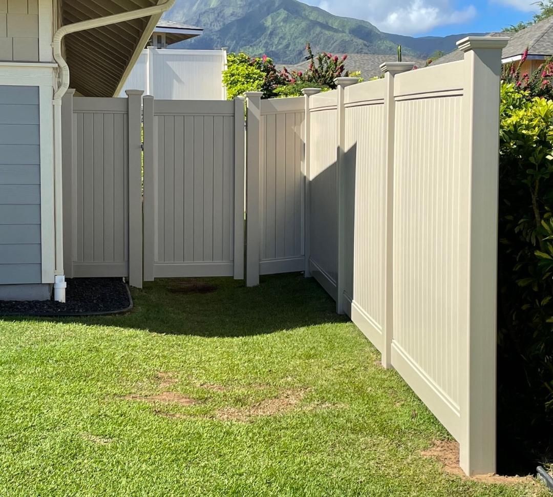 A white fence surrounds a lush green yard in front of a house.