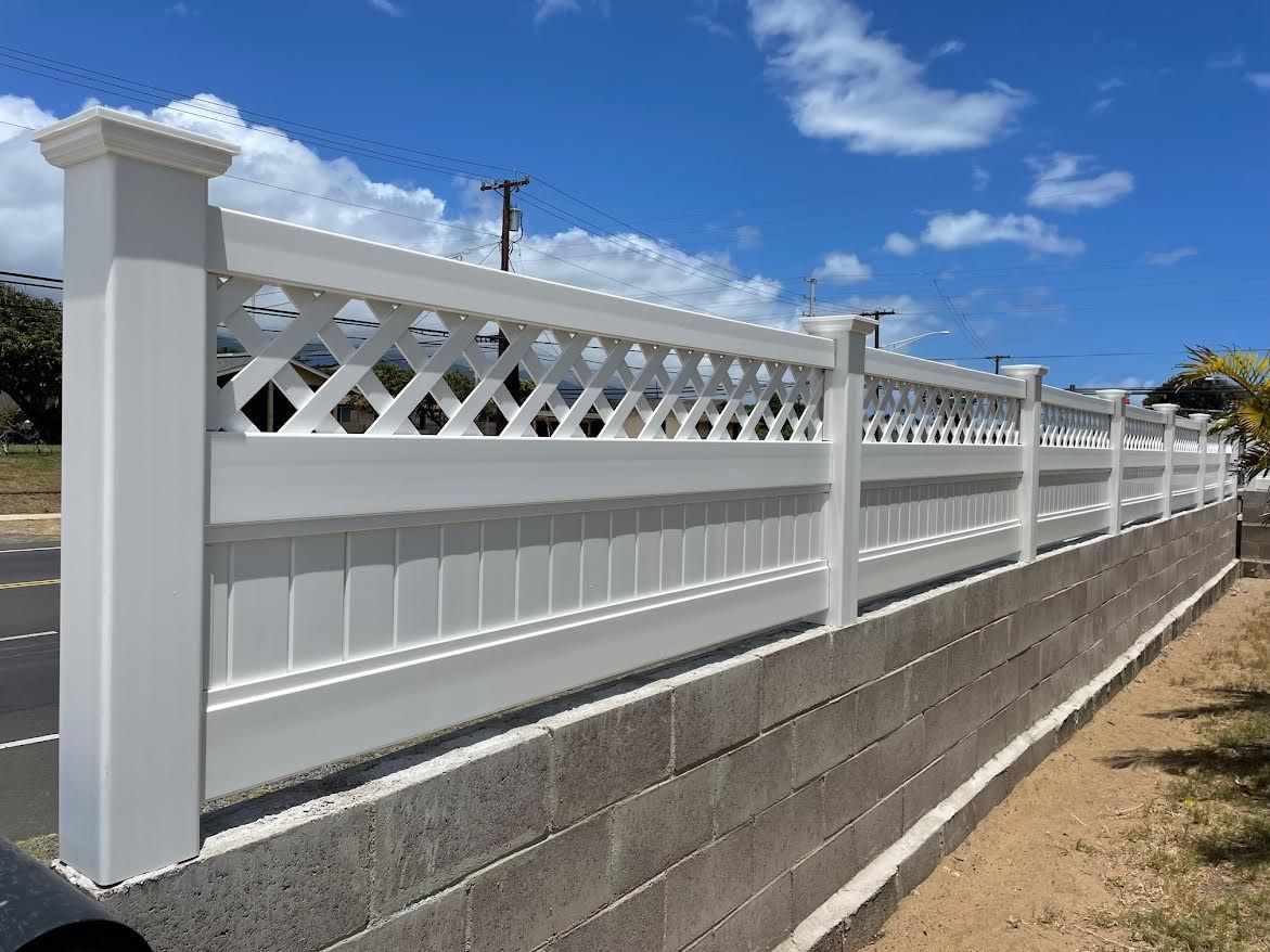 A white lattice fence is sitting on top of a brick wall.