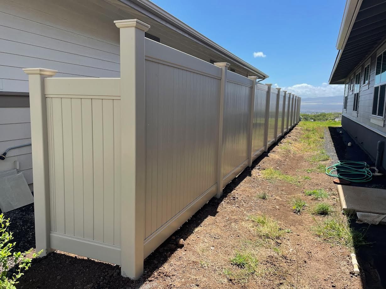 A long white fence is sitting next to a house.