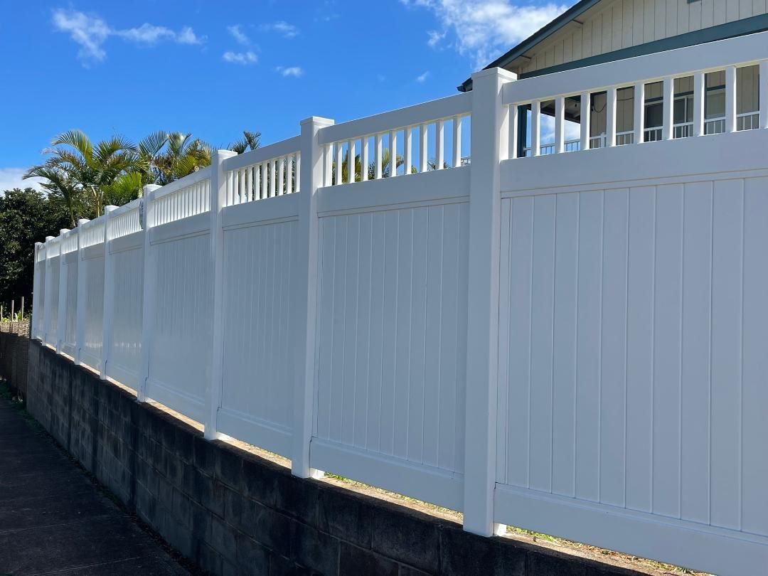 A white fence is sitting next to a brick wall.