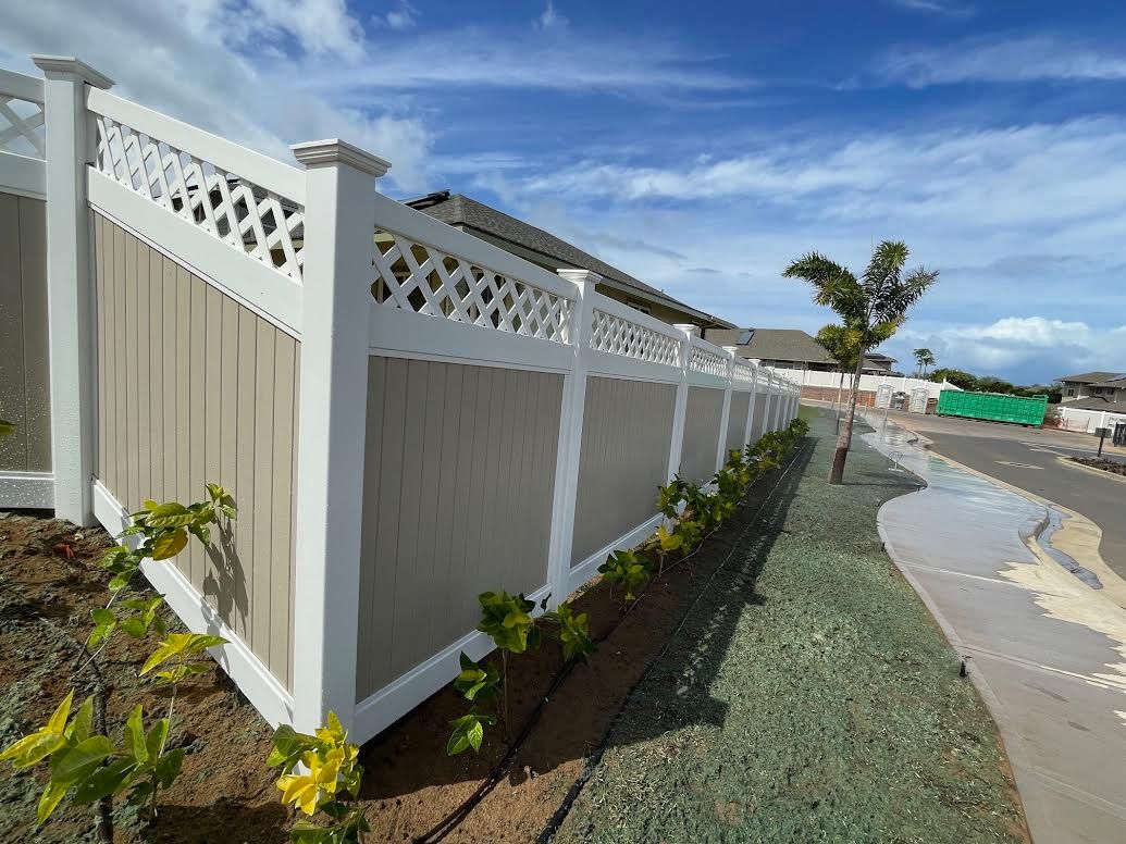 A white and tan fence is sitting next to a sidewalk in front of a house.