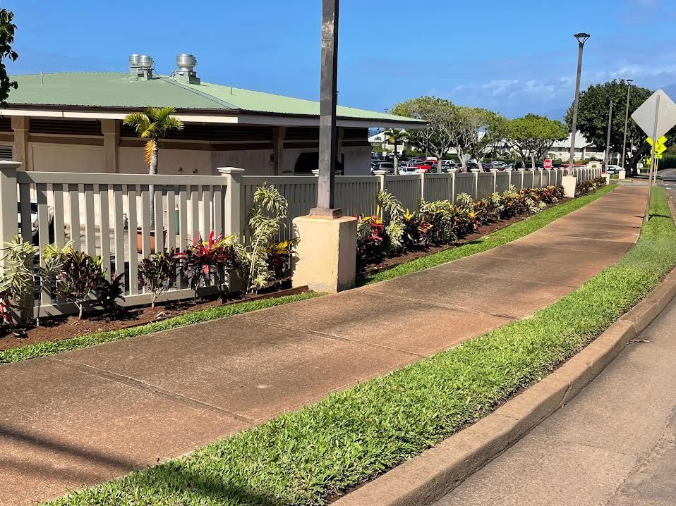A sidewalk leading to a house with a white fence
