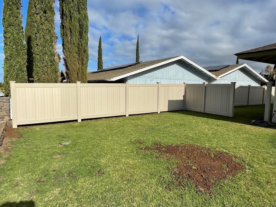 A white fence surrounds a lush green yard in front of a house.