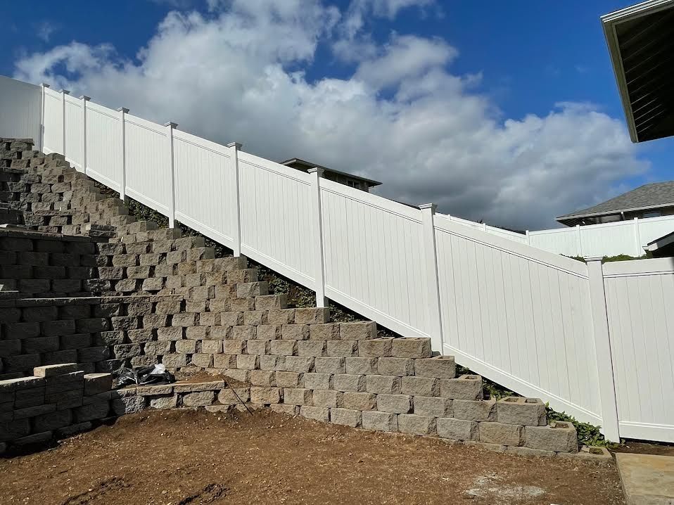 A white fence is sitting on top of a brick wall.
