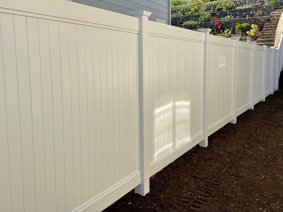 A white fence is sitting in the dirt in front of a house.