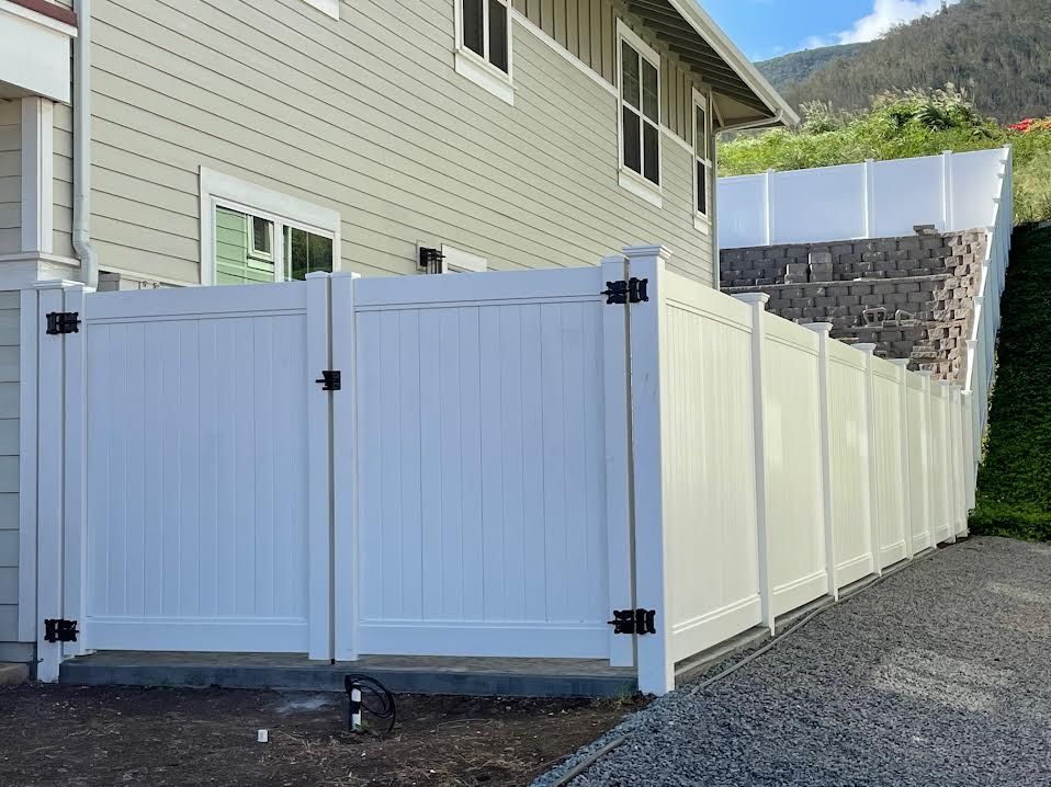 A white fence with a gate is in front of a house.