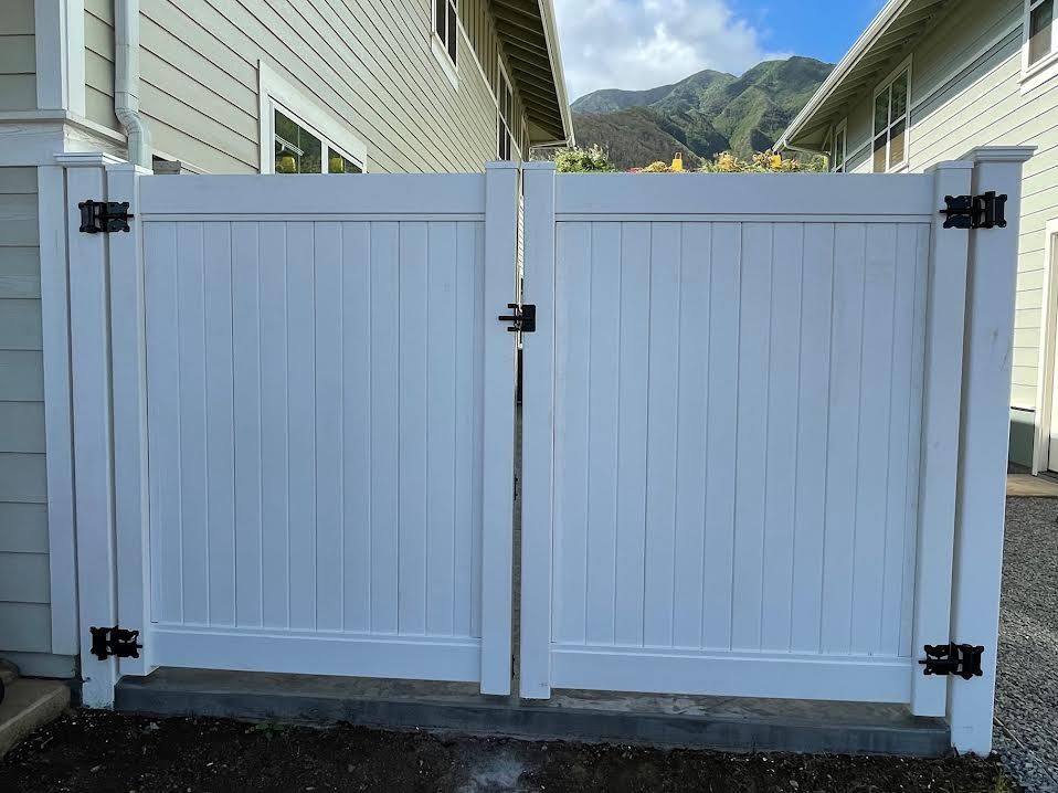A white fence is sitting in front of a house with mountains in the background.