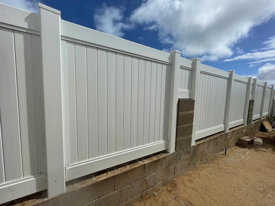 A white fence is sitting next to a brick wall.
