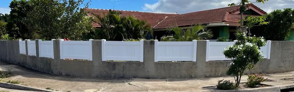 There is a white fence in front of a house.