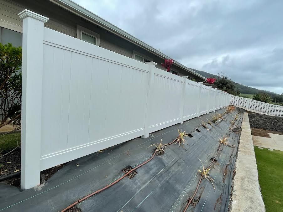 A white fence is sitting on top of a black tarp in front of a house.